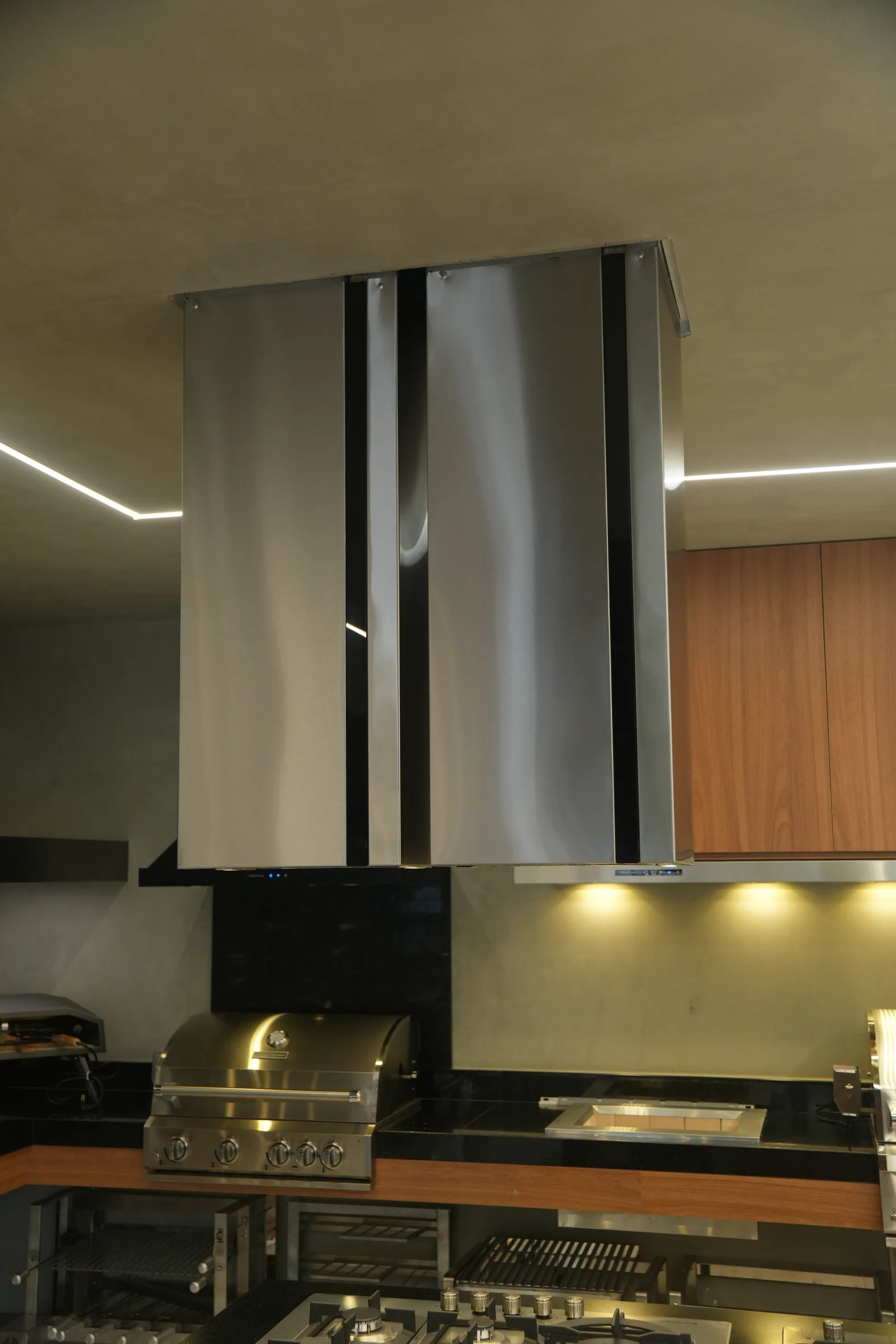 Coifa Máxima Viena de ilha em inox sobre bancada de cocção no showroom